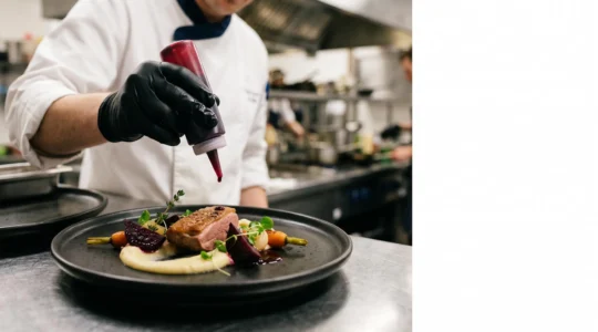 Chef professionnel dressant avec précision une assiette gastronomique colorée dans une cuisine soignée